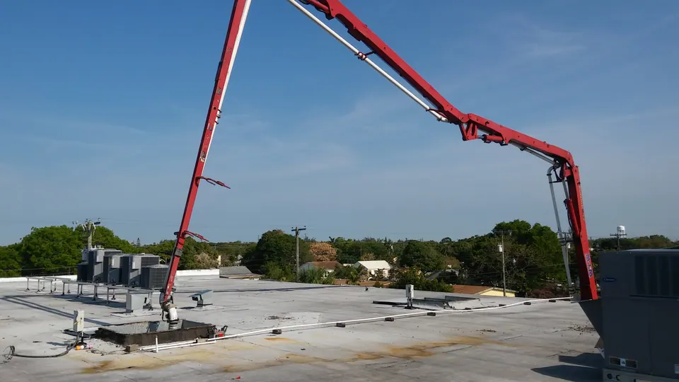 Red boom pump placing concrete on a rooftop slab