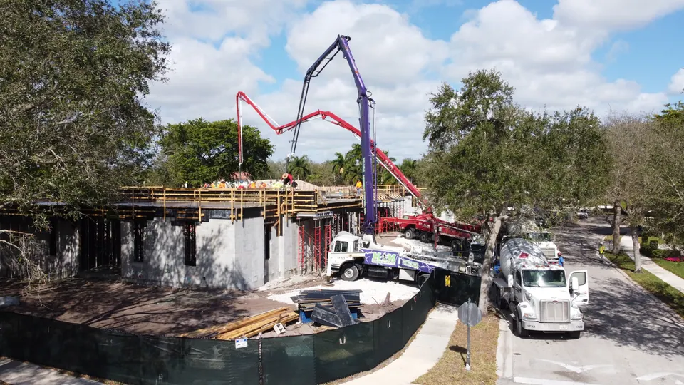 Boom pump and mixer trucks at a multi-story building under construction