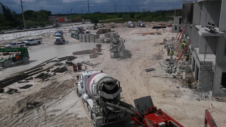 Mixer truck feeding a concrete pump on a large job site, aerial view