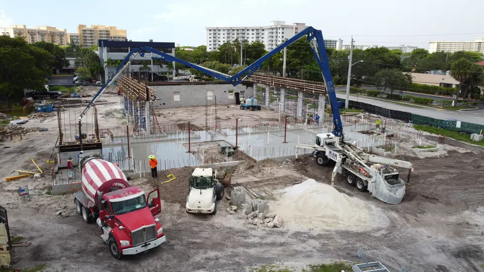 Boom pump and mixer trucks on a commercial pour, aerial view