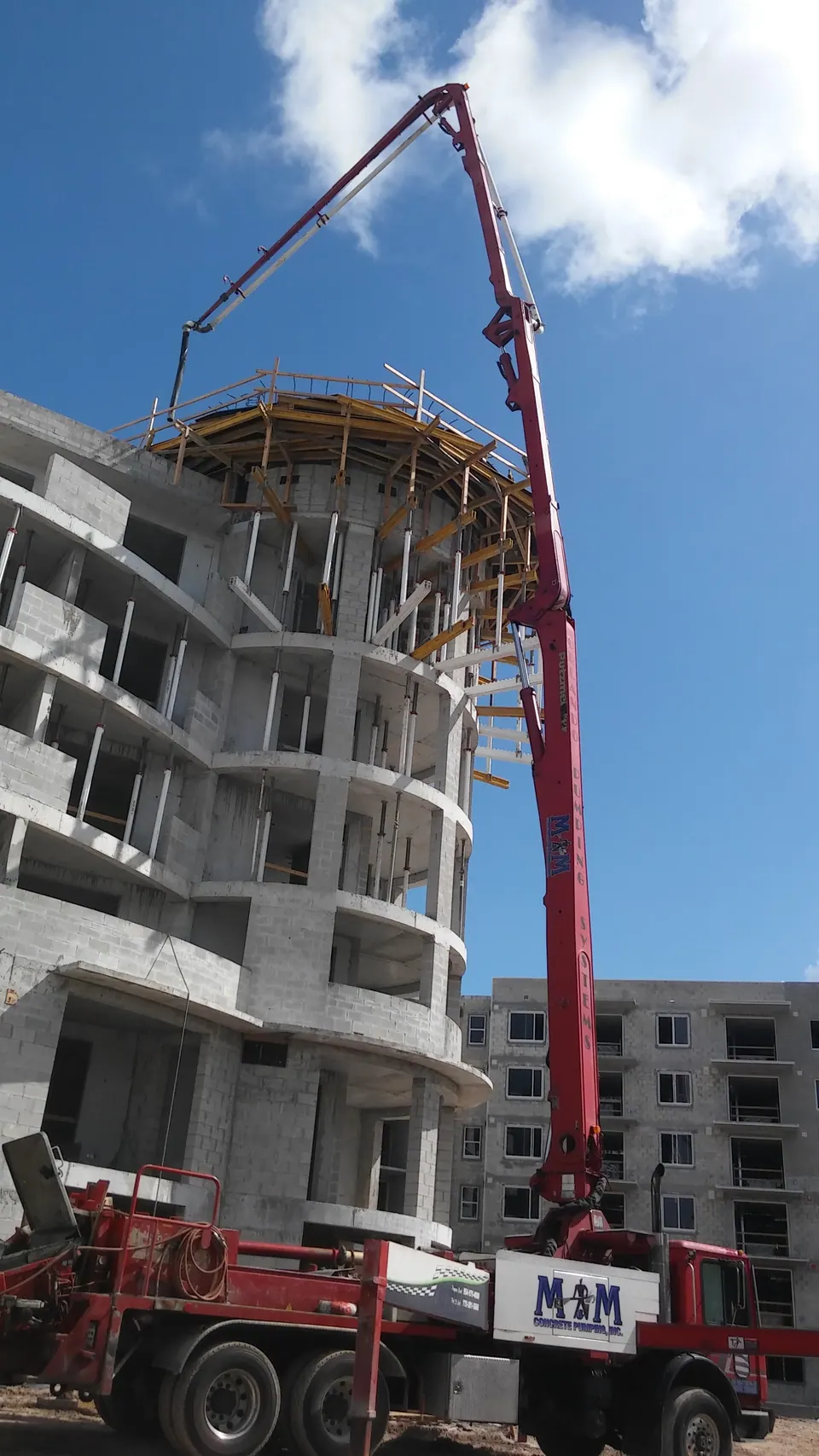 Boom pump beside a concrete high-rise under construction